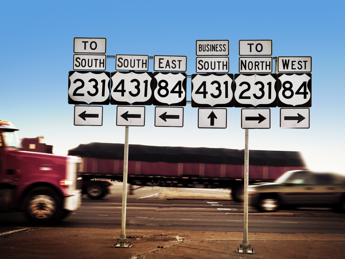 Traffic on busy highway passing by road signs. Horizontal shot.