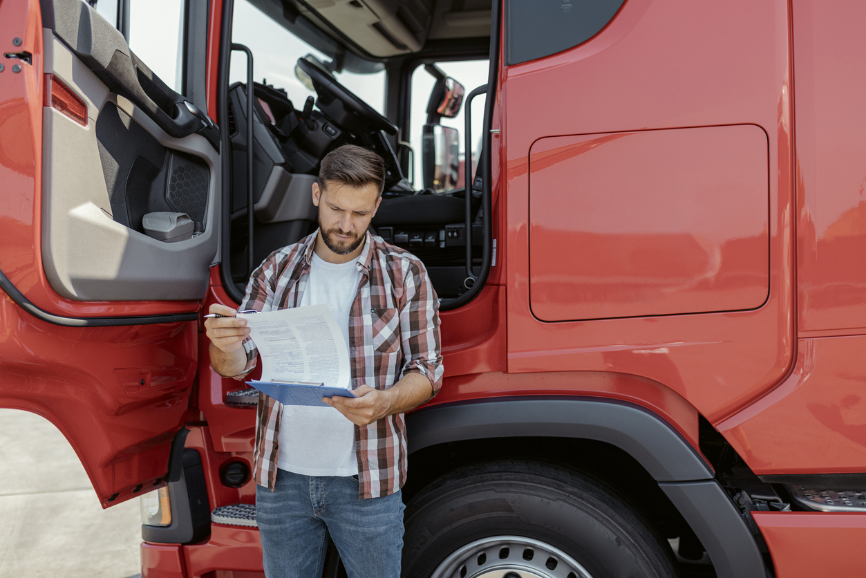 Male Trucking Company Dispatcher Going Through Checklist on Parking Lot